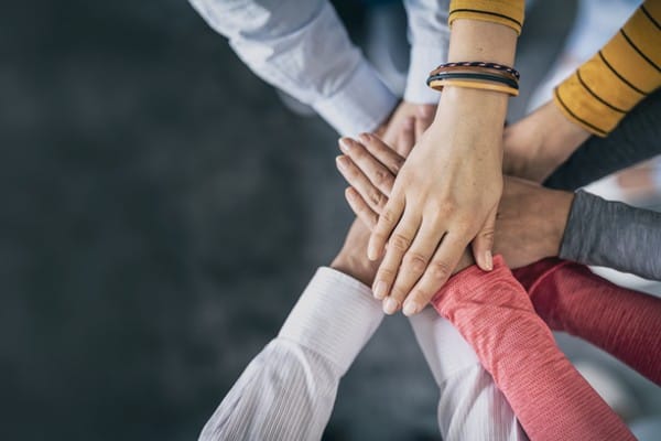 Hands huddle up representing a work team coming together