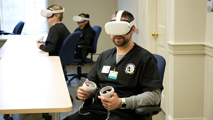Three Purdue Global nursing students sit at a table wearing Meta Quest headsets