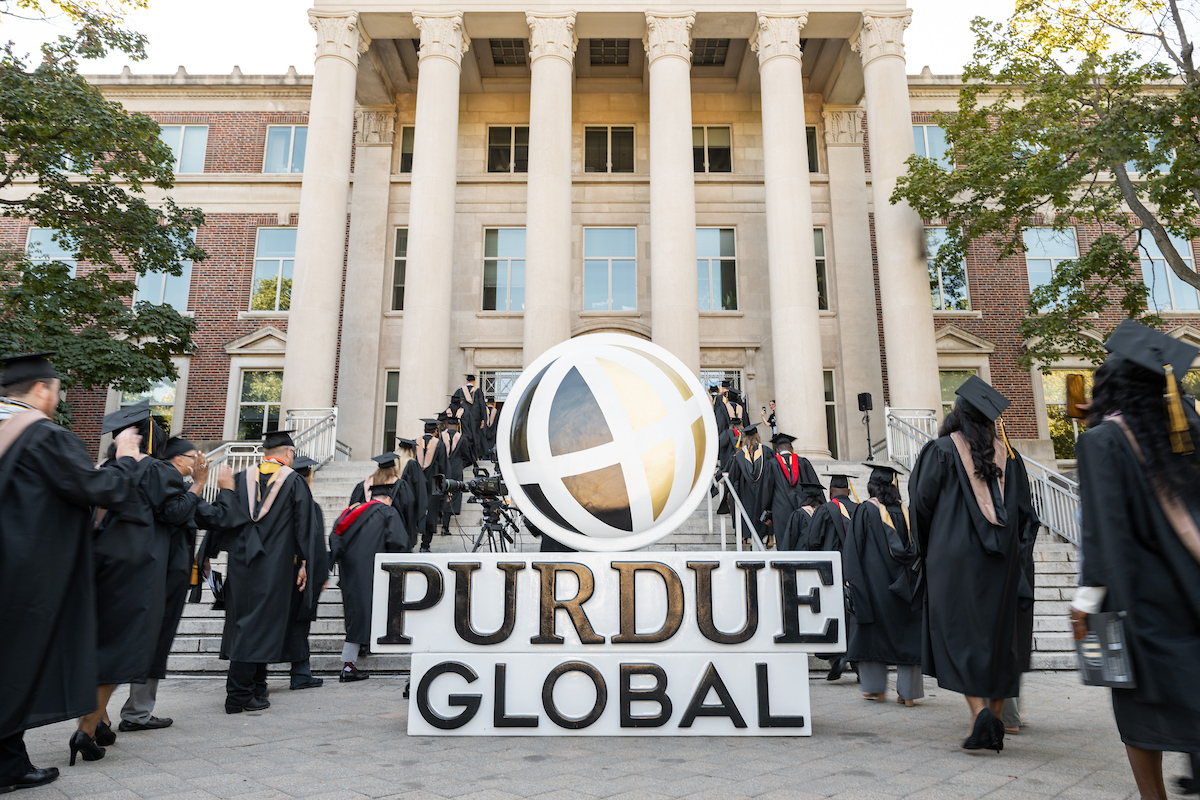 alt: Graduates walking on campus. 