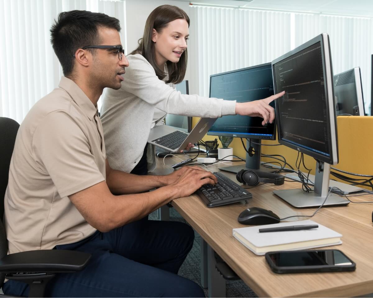 Cybersecurity professionals pointing at information on a computer screen