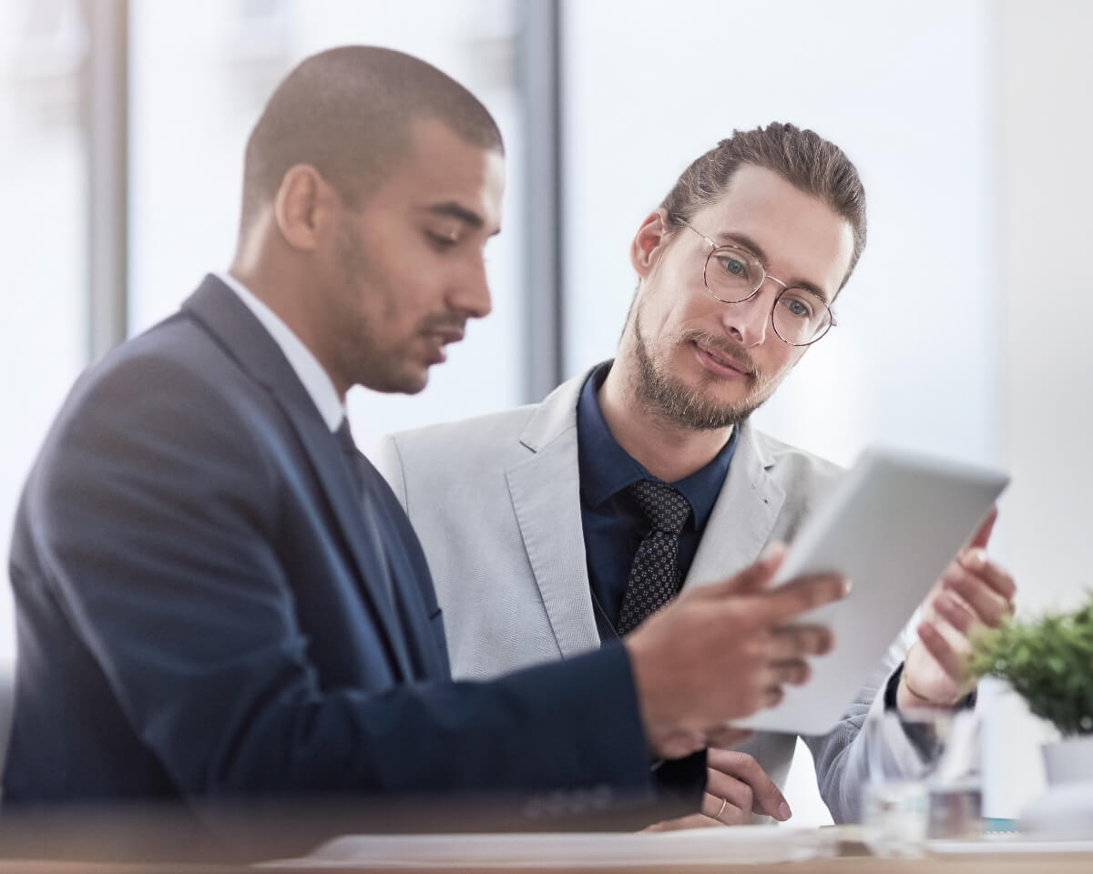 Two accounting professionals review information on a tablet in a meeting room