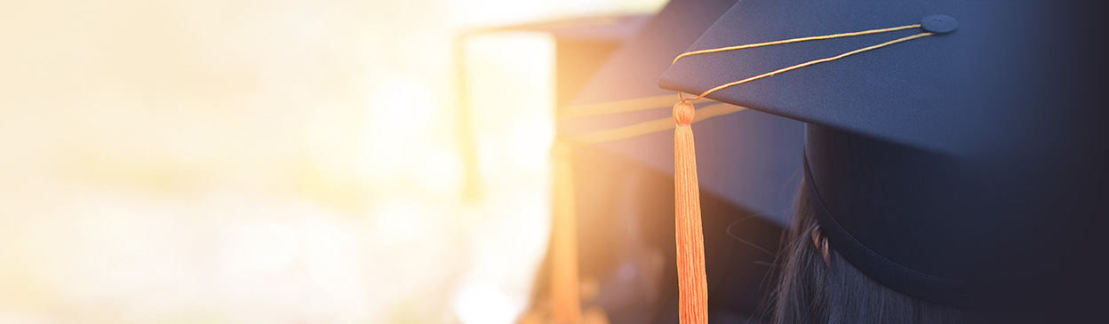student wearing cap and gown with back to camera and brightly lit background