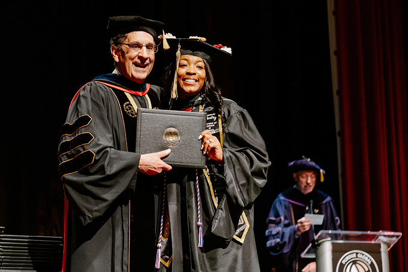 Purdue Global Chancellor handing a student her diploma at the graduation celebration