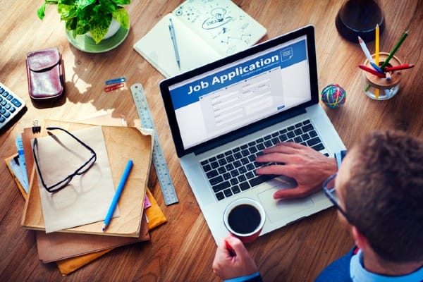 A student works on job applications on his laptop.
