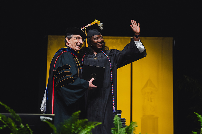 Purdue Global Chancellor Frank Dooley celebrates with a graduate onstage during winter commencement ceremonies.
