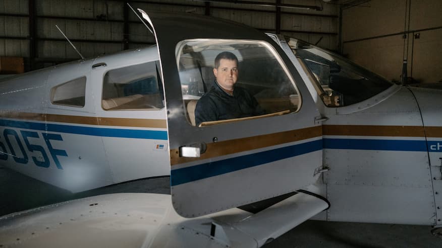 Adrian Mullins sitting in a small airplane in a hanger