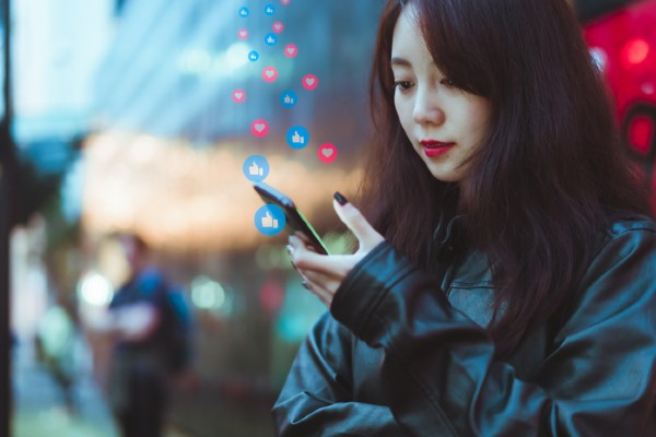 A woman scrolls through her social media accounts on her phone.