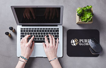 overhead view of student typing on laptop, Purdue Global mouse pad to the right