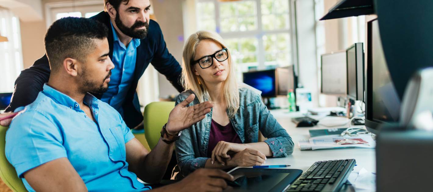 group of professionals discussing something on a computer monitor
