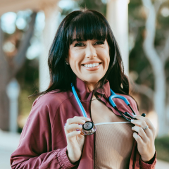 A nurse in red scrubs with a blue stethoscope.