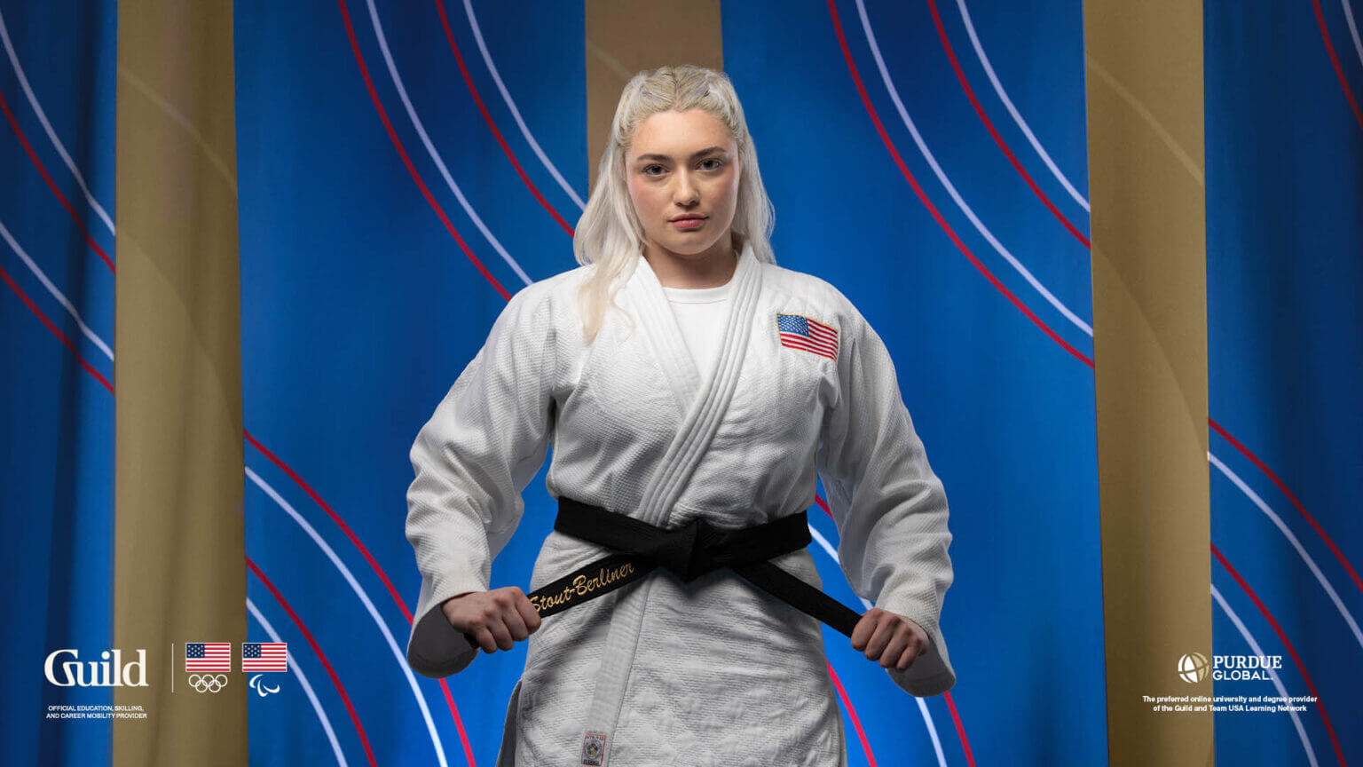 Nicole smiles, wearing a white gi against a blue background.