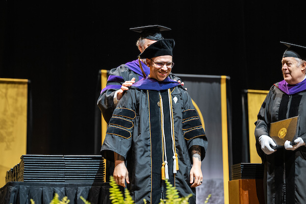 A Purdue Global Law School graduate receives hooding during graduation.