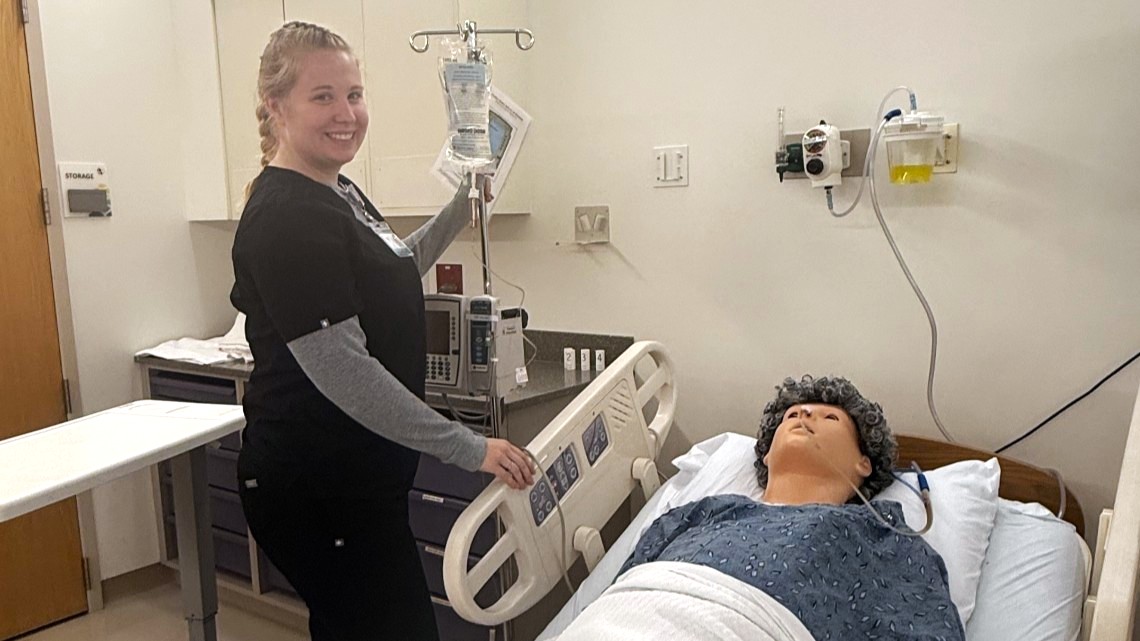 Cap: Purdue Global nursing student Grace Newmarker works in Purdue Global’s simulation center at Northern Light Eastern Maine Medical Center. (Photo provided)
Alt: A Purdue Global nursing students in black scrubs working with a manikin.