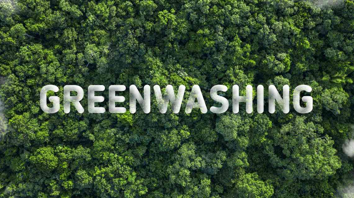 View of a green forest with white letters spelling “GREENWASHING” across it.