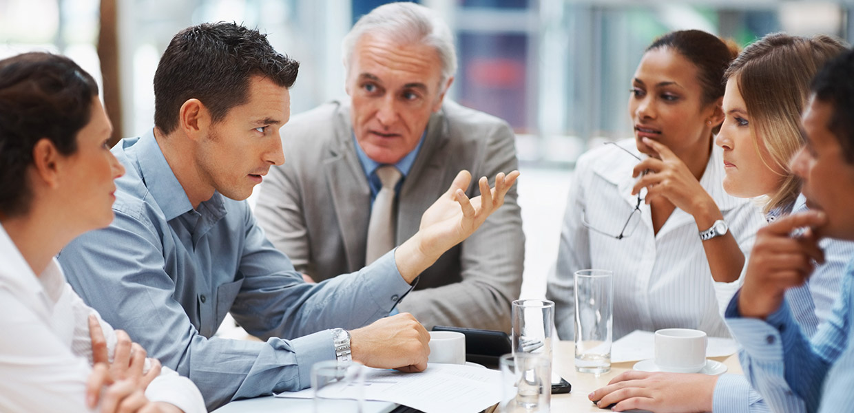 A group of coworkers have a discussion while sitting at a table.