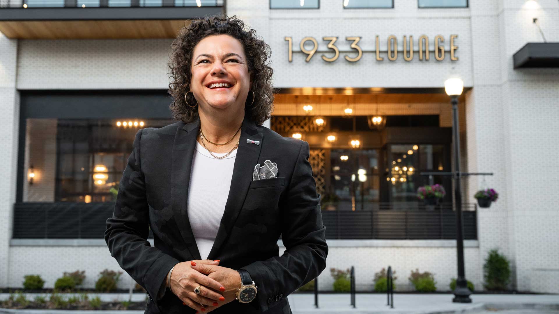 Leanna Chroman, in a white shirt and black blazer, stands in front of one of her restaurants, 1933 Lounge in Carmel, Indiana.