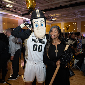 a Purdue Global graduate and Purdue mascot at the Black and Gold celebration