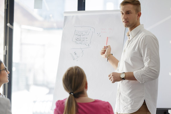 A man stands in front of a whiteboard and makes a presentation