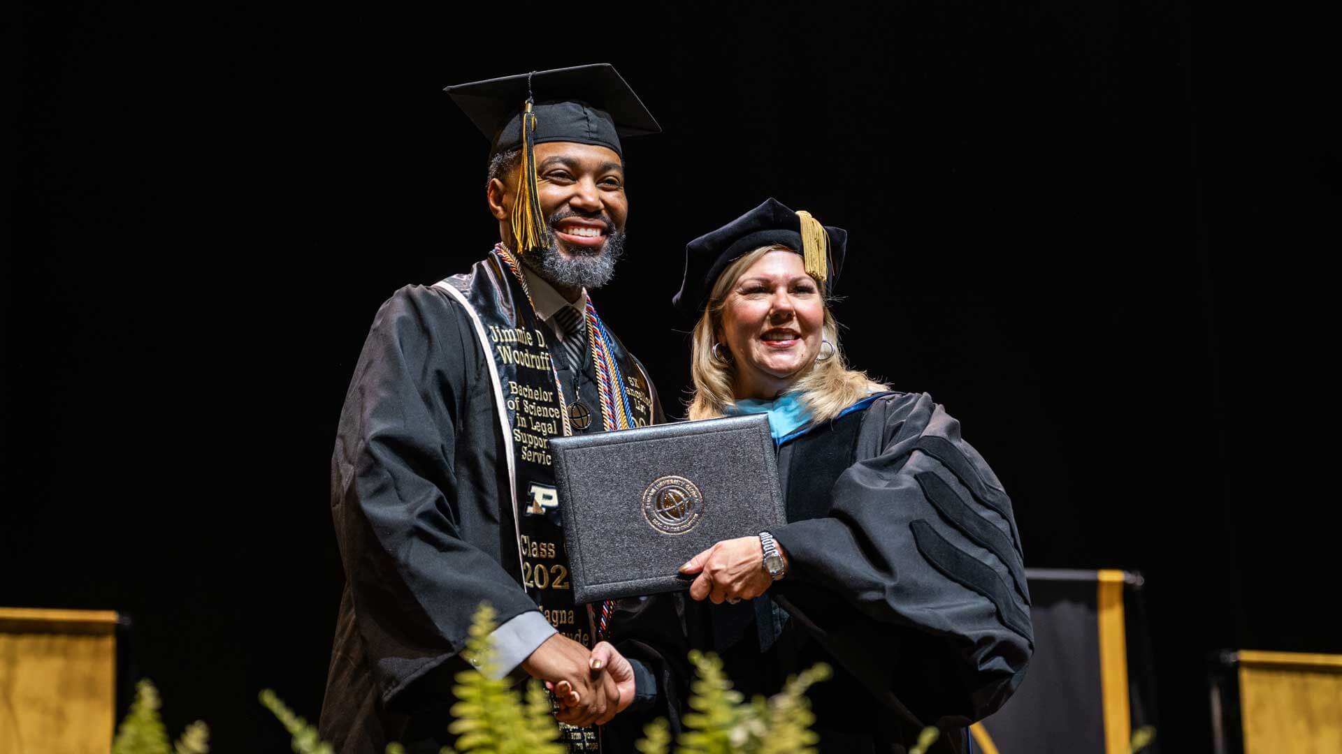 Jimmie Woodruff in cap and gown, holding his diploma