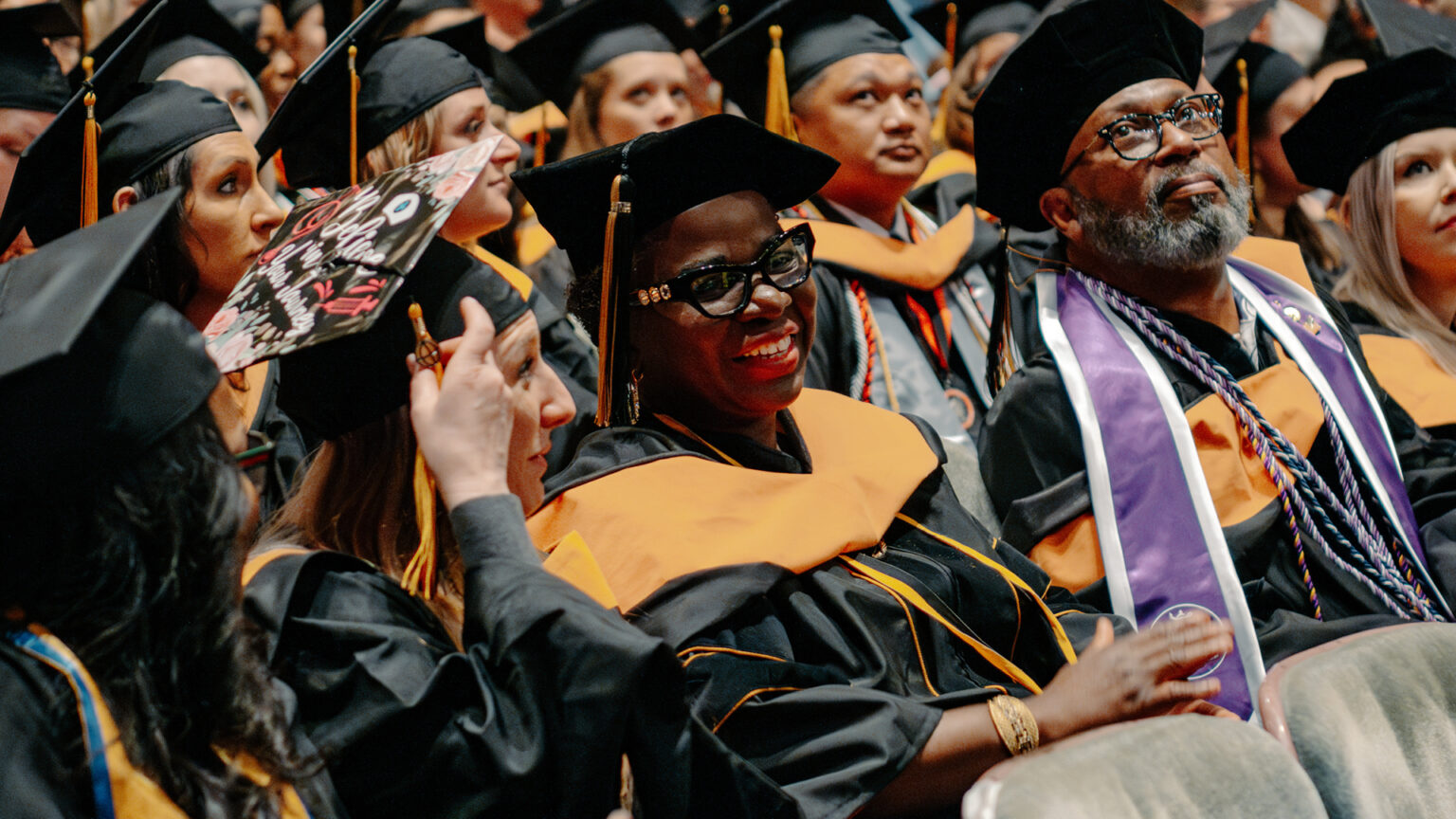 Sade Adeojo sits in the crowd at her Purdue Global graduation for her postgraduate certificate.  