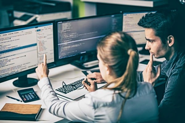 Two information security analysts look at a computer monitor