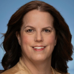 A woman in a gold jacket on a blue background.