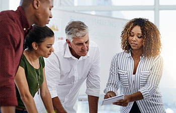 Group of people leaning on a table looking at a document