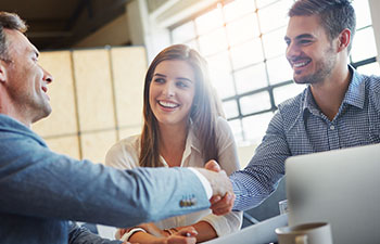Men shaking hands next to smiling woman