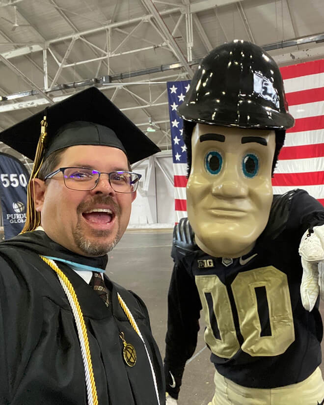 Brewer poses for a selfie in his cap and gown with Purdue University’s Purdue Pete.