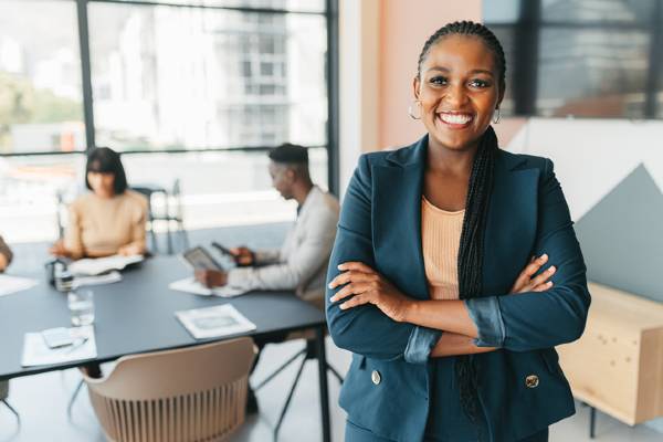 Female leader standing with arms crossed at work during a meeting for planning and strategy.