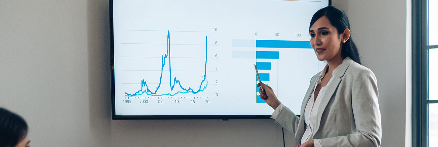 professional pointing to charts on a smartscreen in a meeting room