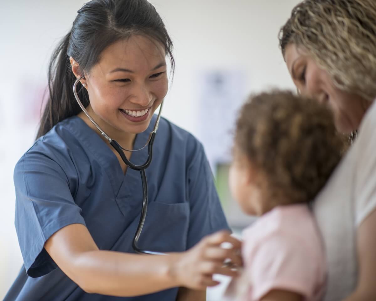 Smiling nurse checks a baby with a stethoscope