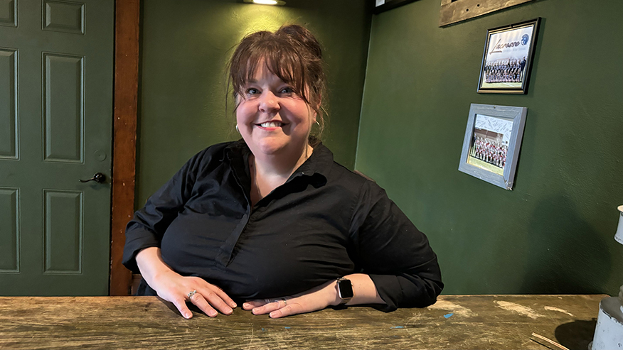 Jessi Eaton sitting at a wooden table in a room with dark green paint