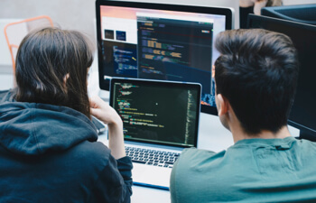 two students studying a large monitor