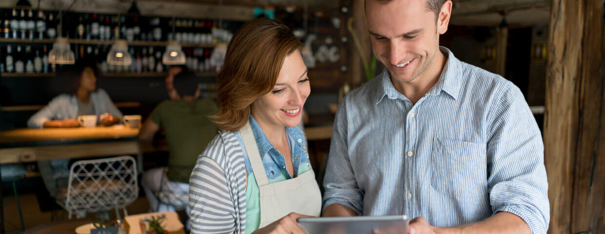 Two employees in a fancy restaurant looking at an ipad and smiling