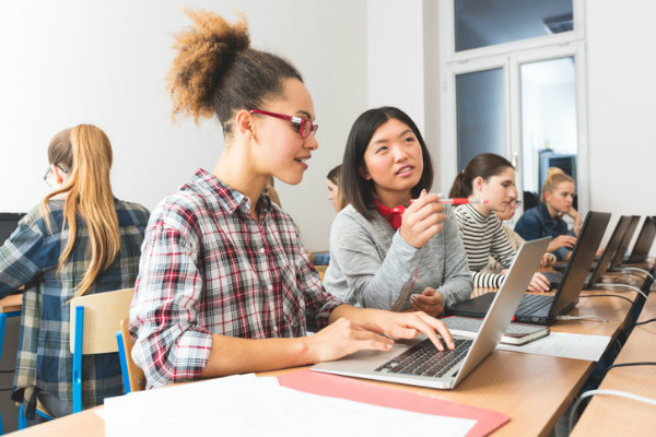A photo of two girls studying computer technology on a laptop.