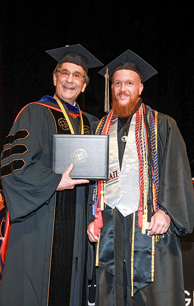 Chancellor Frank Dooley holds a diploma and stands with Jeff Vandergriff at a Purdue Global graduation ceremony