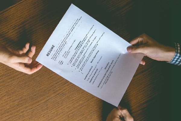 Close up of a resume being handed over from job seeker to interviewer