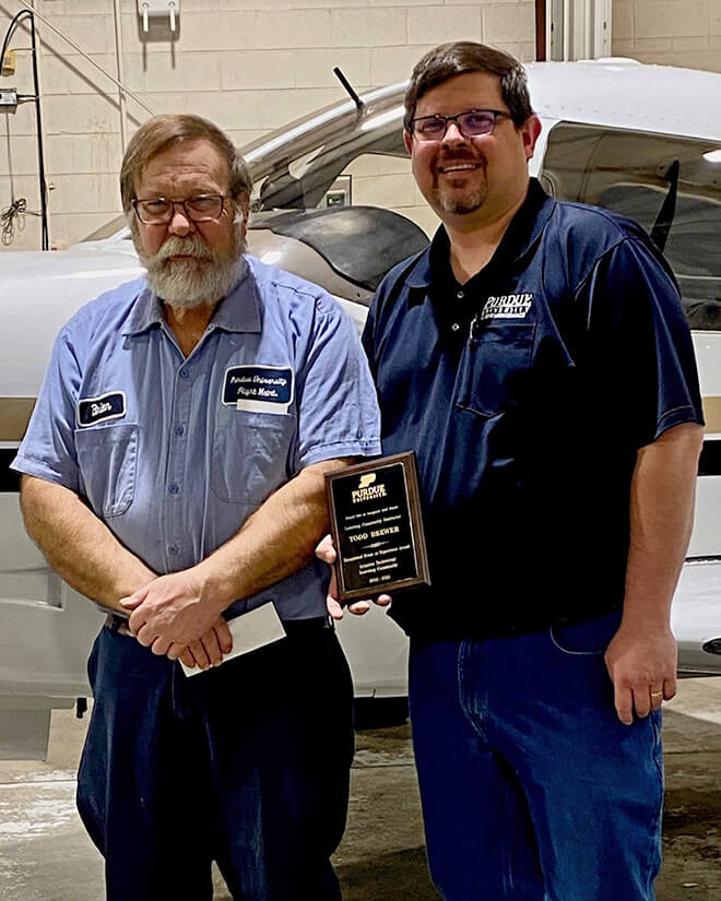 Brewer stands with a colleague holding his learning community award.