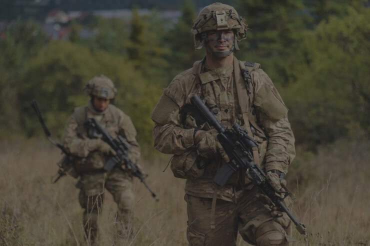 two soldiers carrying rifles walking in a field