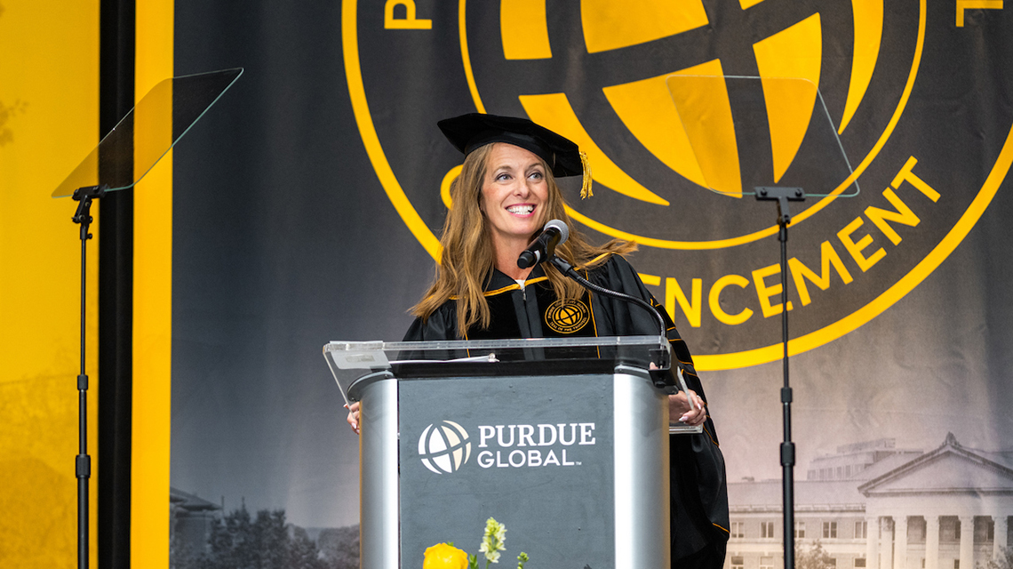A woman in a black robe behind a Purdue Global podium.