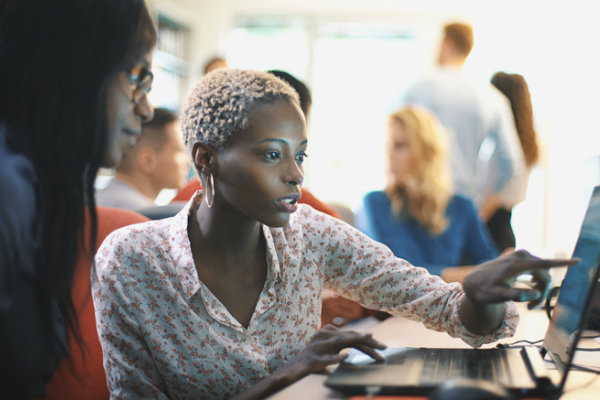 A photo of two women looking at data on a laptop.