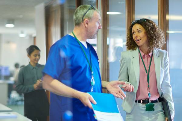 Health care administrator talking with medical practitioner.