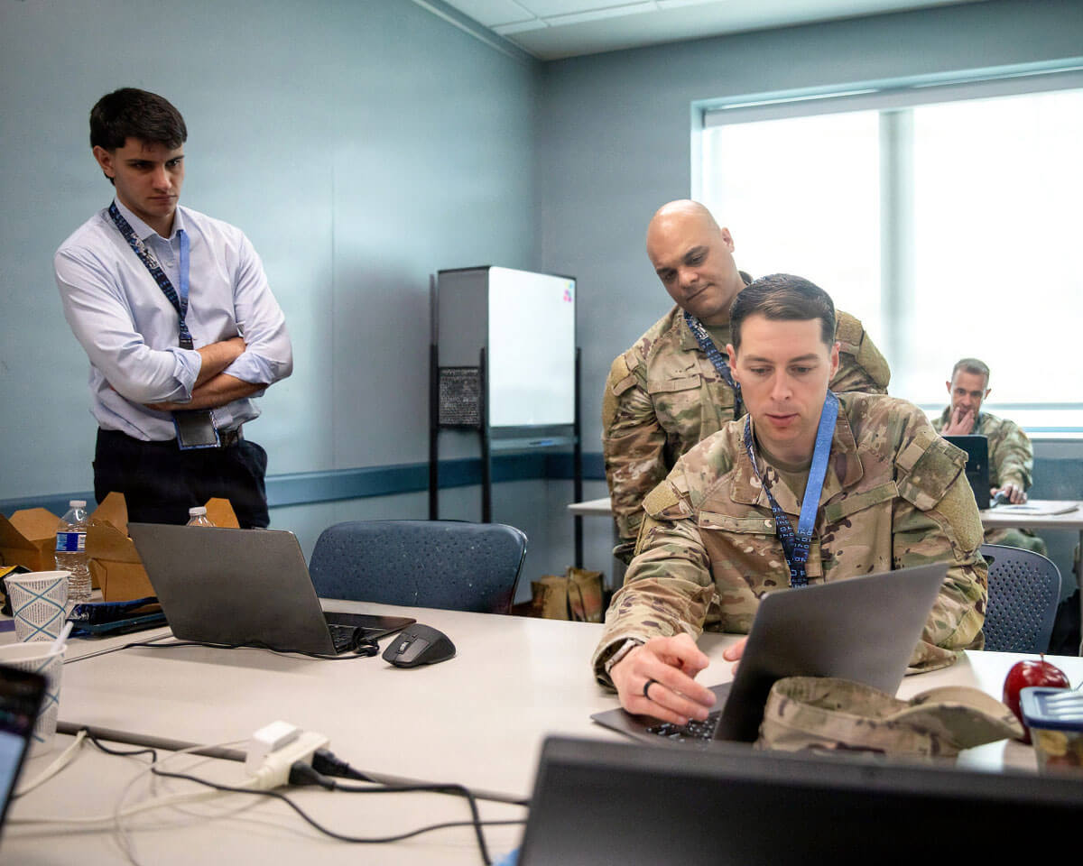 group of professionals in military uniforms discussing content on a laptop