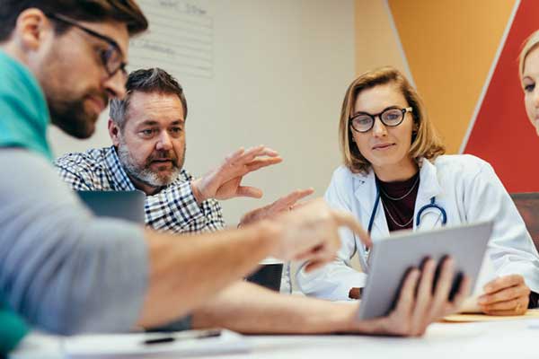 A group of nurses look at a tablet.