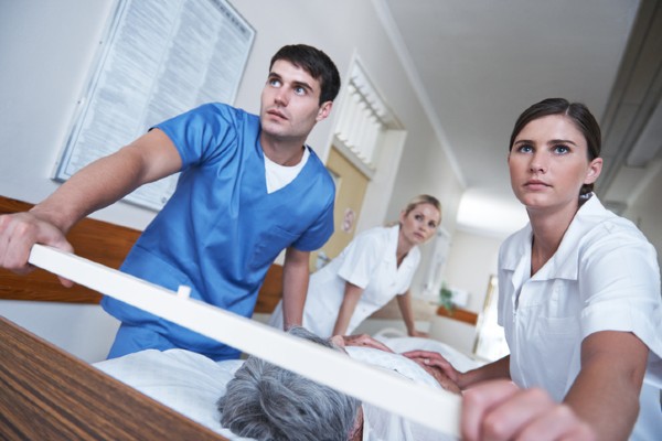Three nurses wheel a patient into surgery.