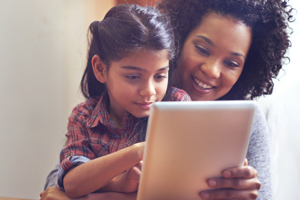 Woman with small child on lap looking at a tablet