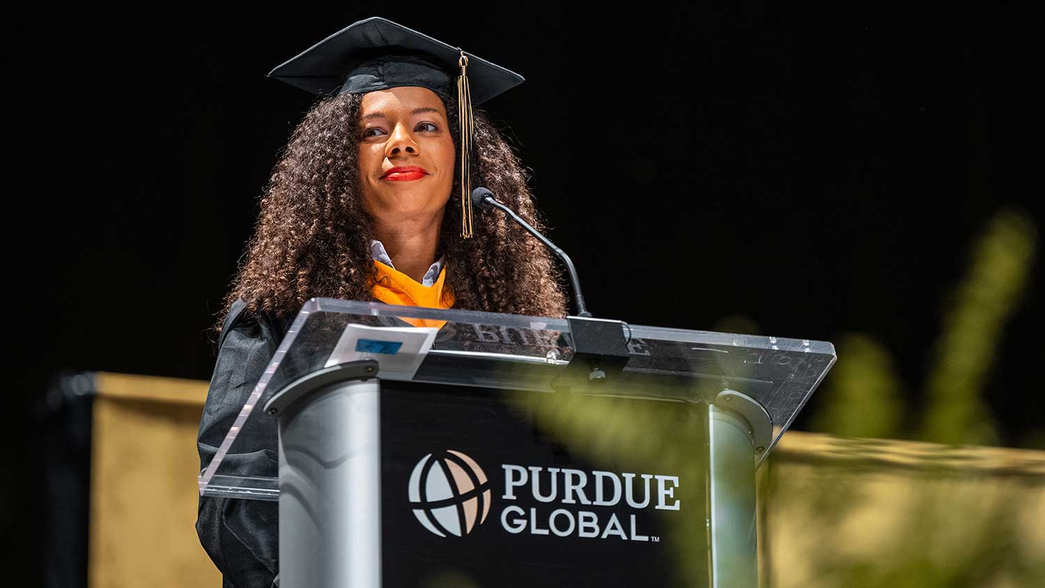 Nicole Hicks standing at a podium speaking at graduation
