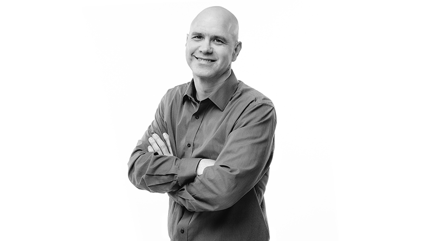 Black-and-white photo of Robert Hart, arms crossed, smiling.