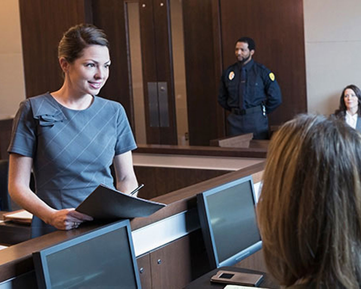 Woman in plaid dress speaking to a jury in a courtroom